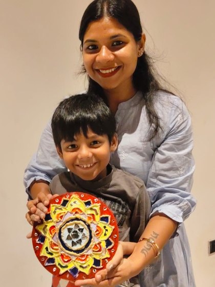 Soumya and her son smiling and holding the mirror-work mandala he made